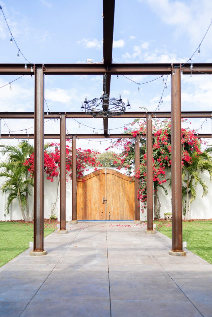 Venue 650 open garden area with high white walls, string lights and a large wooden entry gate. One of the best wedding ceremony locations in Lakeland