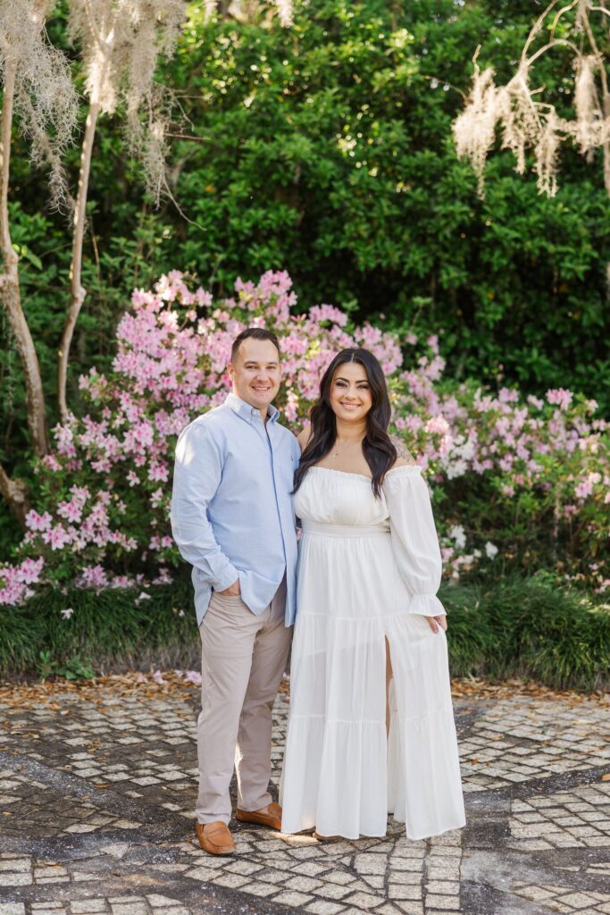 Couple beneath Spanish moss with pink azaleas blooming behind them