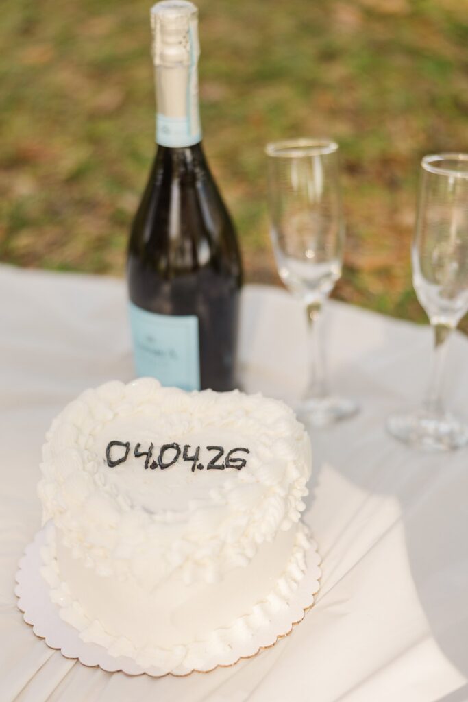 Champagne, glasses and a small white cake topped with the couple's wedding date