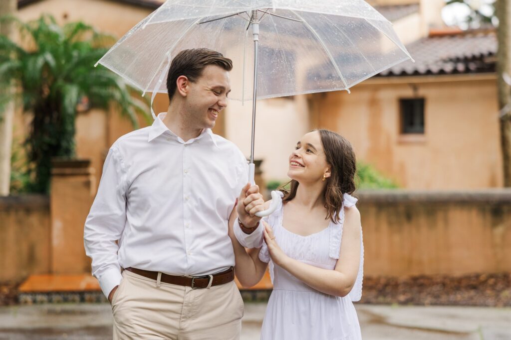 Couple sharing a clear umbrella in the rain in front of El Retiro's stucco walls