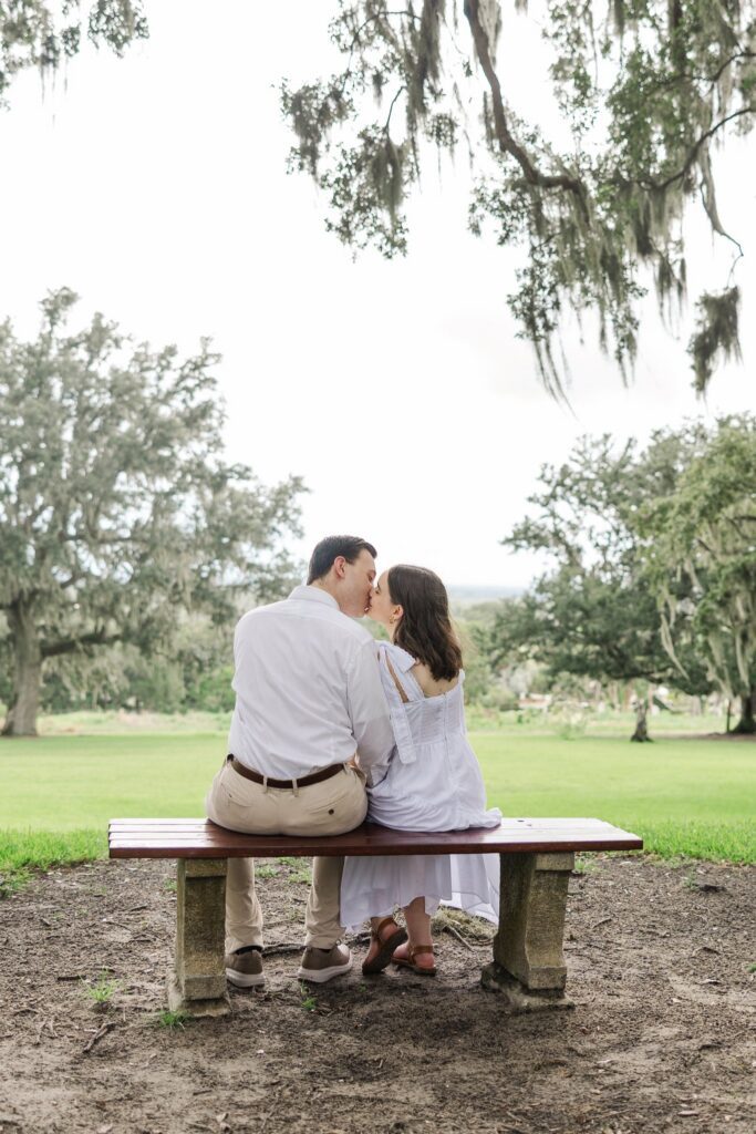 Couple sharing a kiss on the hilltop bench, looking out over the countryside below Iron Mountain