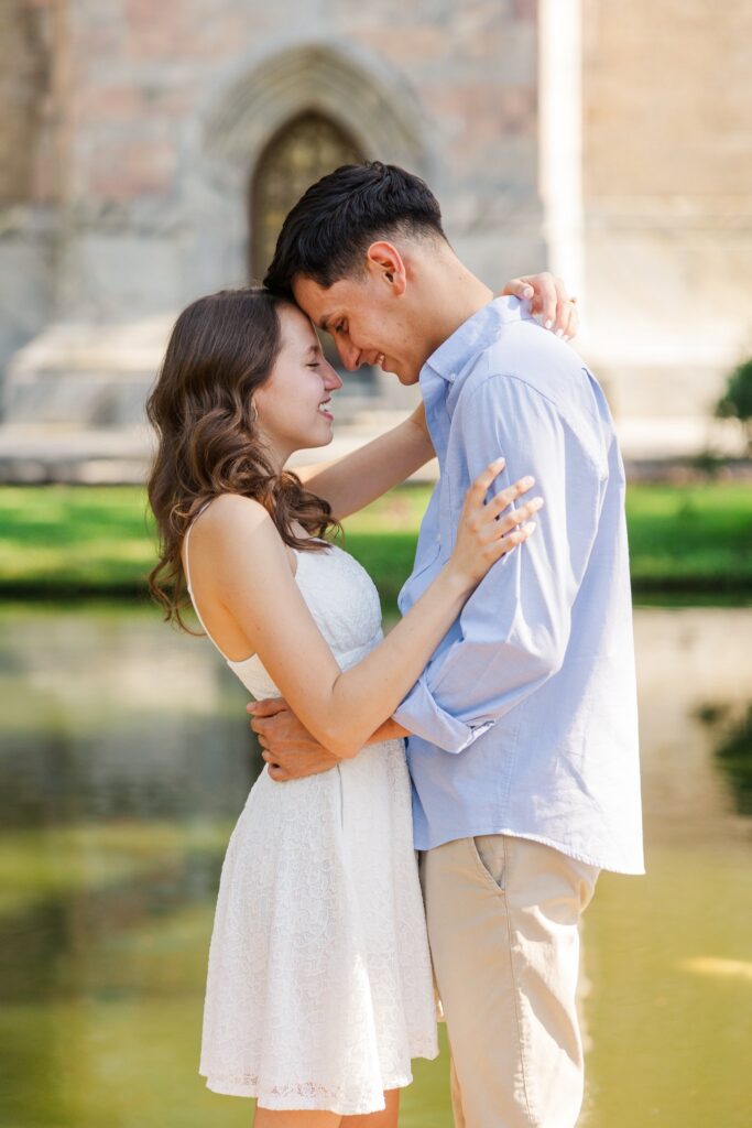 Couple touching foreheads by the moat with the tower's arched door behind them