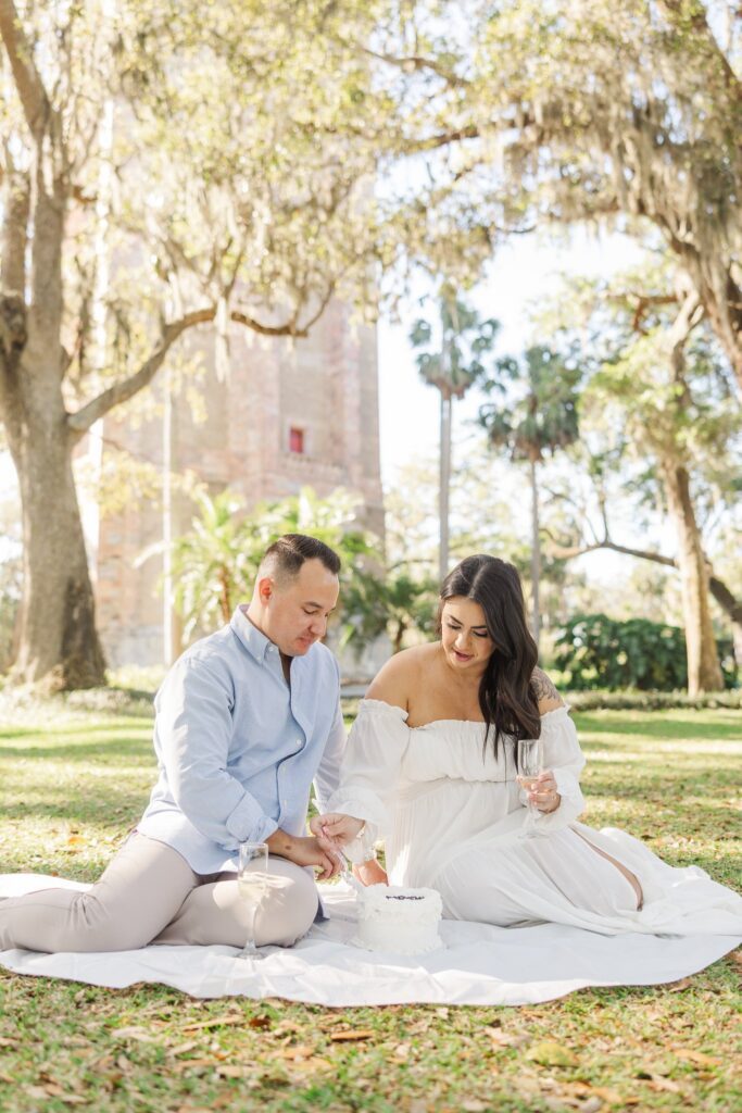 Couple sharing a picnic on the lawn under live oaks, with the Singing Tower in the distance