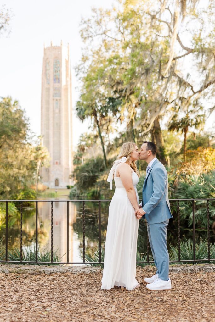 Couple kissing at the reflection pool railing at golden hour, with the Singing Tower rising behind them