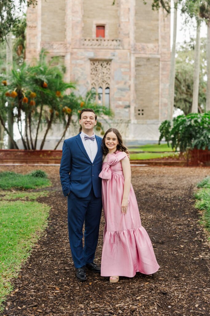 Couple in a pink gown and blue suit on the path below the Singing Tower's facade
